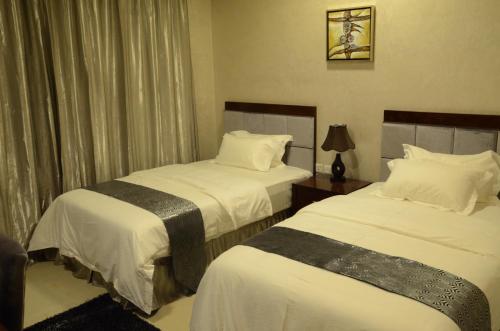 una camera d'albergo con due letti con lenzuola bianche di Reef Hotel Aparts (Tabasum Group) ad Ajman