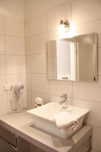 a white bathroom with a sink and a mirror at Hotel Garni Kleist am Kurfürstendamm in Berlin