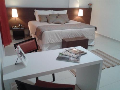 Un dormitorio con una cama y una mesa con un libro en Hotel Cristal, en Turmalina