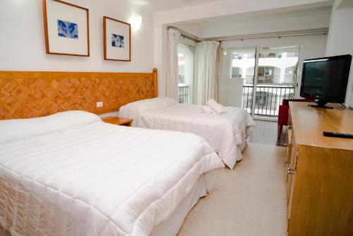 a hotel room with two beds and a television at Oceanfront condo at voted best Cancun sandy beach in Cancún