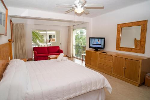 Un dormitorio con una gran cama blanca y un televisor. en Oceanfront condo at voted best Cancun sandy beach, en Cancún