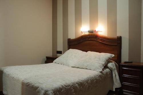 1 dormitorio con cama blanca y cabecero de madera en Hostal Ana Belen, en Madrid