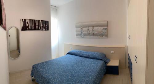 um quarto com uma cama azul e um espelho em RESIDENCE EL PALMAR FRONTE MARE, FRONTE SPIAGGIA (5 metri), FRONTE PISCINA (4 metri) em Lido di Jesolo