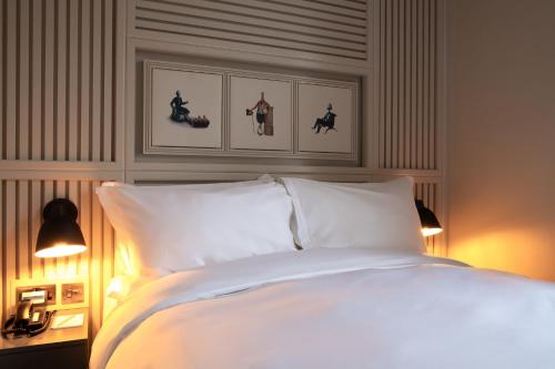 a bedroom with a bed with white sheets and two lamps at Home Grown - Private Member's Club in London