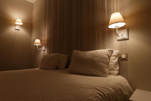 - une chambre avec un lit avec deux oreillers et deux lumières dans l'établissement Appart'Hôtel Sainte Trinité, à Troyes