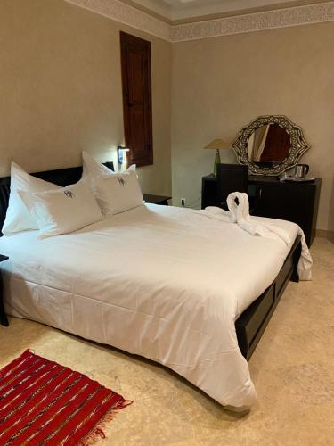 a large white bed in a bedroom with a mirror at LES JARDINS DE MARRAKECH in Marrakech