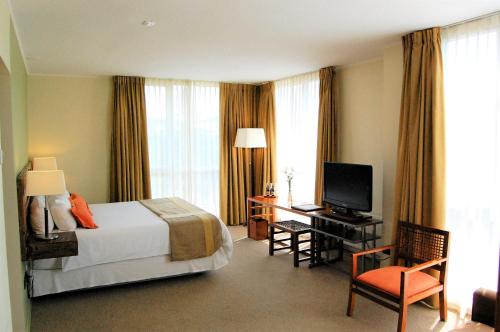 Habitación de hotel con cama y escritorio con TV. en Solace Hotel Puerto Varas, en Puerto Varas