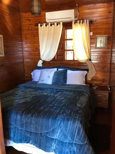 a bedroom with a bed with blue sheets and a window at RANCHO COSTEIRO AGROTURSIMO E BALNEARIO E PESQUEIRO in Pôrto Xavier