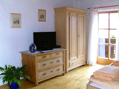 a bedroom with a television on a wooden dresser at Ferienwohnung Schartner in Eggstätt