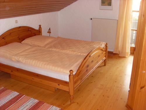 Cama de madera en un dormitorio con suelo de madera en Ferienwohnung Schartner, en Eggstätt