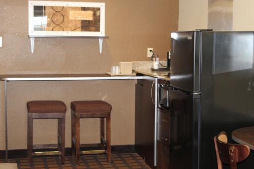 a kitchen with a refrigerator and two bar stools at Microtel Inn & Suites by Wyndham Harrisonburg in Harrisonburg