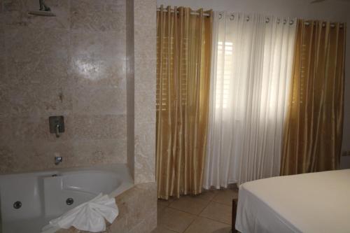 a bathroom with a tub and a shower with curtains at Albachiara Hotel - Las Terrenas in Las Terrenas