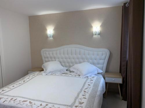 1 cama blanca con 2 almohadas y 2 luces en la pared en Coeur d'Alsace Colmar Vignobles Ouest avec terrasses en Wintzenheim