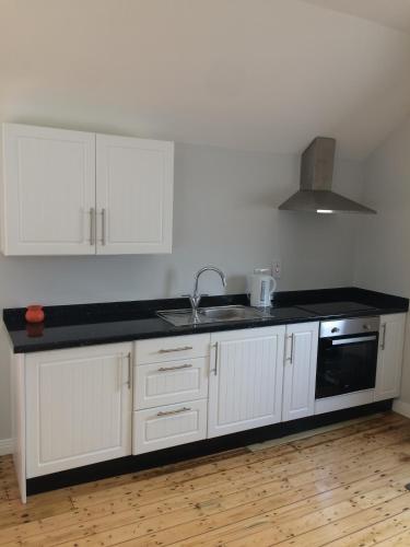 a kitchen with white cabinets and a black counter top at Cosy stylish 1-Bed Apartment in South Armagh in Cullyhanna