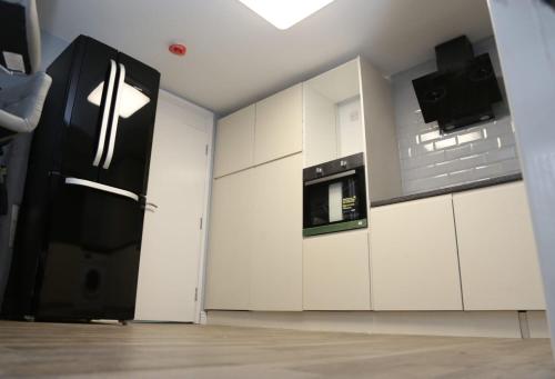 ロンドンにあるBudget 4-Bed House in Woolwichの白いキャビネットと黒い冷蔵庫のあるキッチン