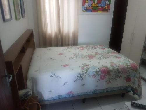 um pequeno quarto com uma cama com um cobertor floral em Residencial santana em Feira de Santana
