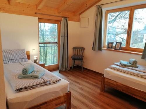 a bedroom with two beds and a chair and windows at Wolke 8 in Bernau am Chiemsee