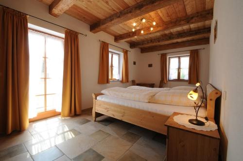 a bedroom with a large bed in a room with windows at Stöttnerhof Urlaub auf dem Bauernhof in Bernau am Chiemsee