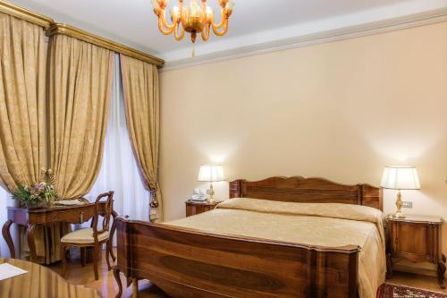 a bedroom with a bed and a table and a chandelier at Villa Fenaroli Palace Hotel in Rezzato