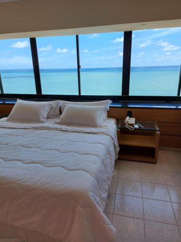 duże łóżko w pokoju z dużymi oknami w obiekcie Hotel Euro Suíte Recife Boa Viagem w mieście Recife