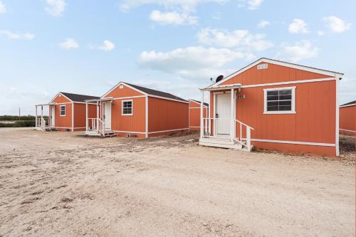 a row of orange modular homes on a dirt road at The Resource Inn -Big Lake TX in Big Lake