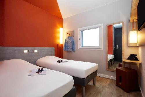 a hotel room with two beds and a mirror at Ibis Budget - Lille Villeneuve D'Ascq in Villeneuve d'Ascq