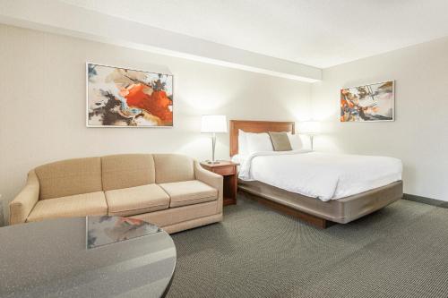 a hotel room with a bed and a couch at Hôtel WelcomInns in Boucherville