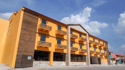 un grand bâtiment jaune avec des touches de bois dans l'établissement ST CRUZ PLUS, à Creel