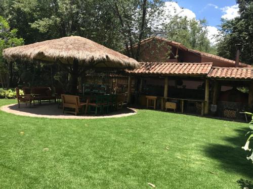 a house with a straw roof and a grass yard at Karina Wasi in Pisac