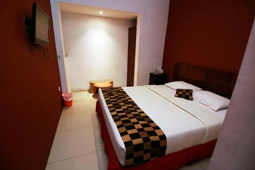 a bedroom with a bed with a checkered blanket on it at Fora Guest House Taman Lingkar in Bandung