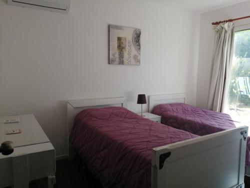 1 dormitorio con 2 camas con sábanas moradas y ventana en Descanso en Piriápolis, en Piriápolis