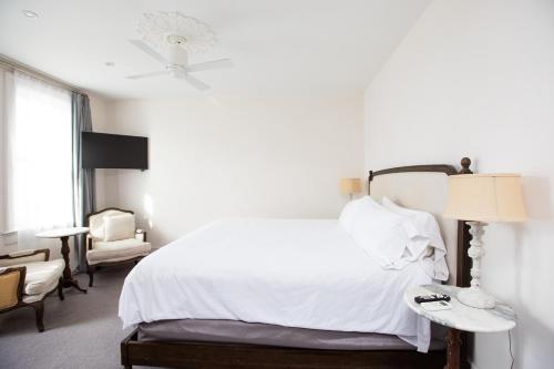 a bedroom with a white bed and a chair at Surf Hotel & Chateau in Buena Vista