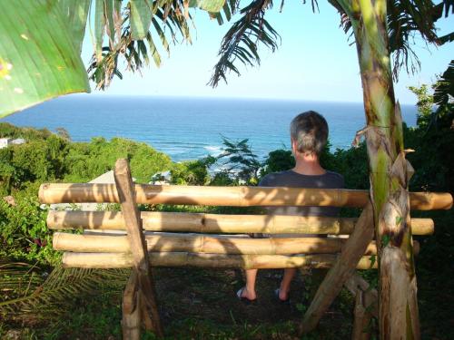 a man sitting on a bench looking at the ocean at Pimento Lodge Resort in Port Antonio