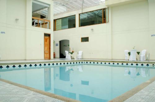 a swimming pool in a building with white walls at Hotel Dinastia Real in Duitama