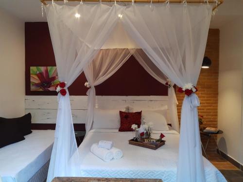 パラチにあるMagias de Paraty Ecopousadaのベッドルーム(白いカーテン付きのベッド1台付)