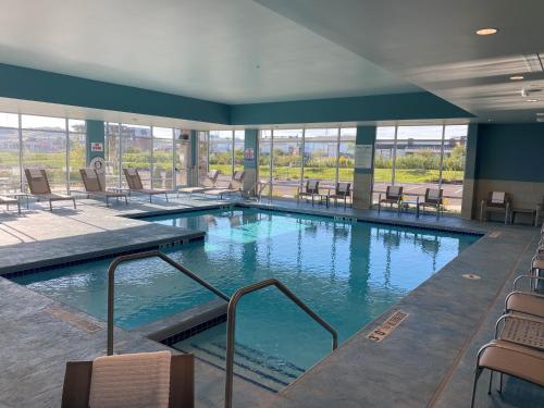 uma grande piscina com cadeiras e mesas num edifício em Holiday Inn Express & Suites - Madison West - Middleton, an IHG Hotel em Middleton