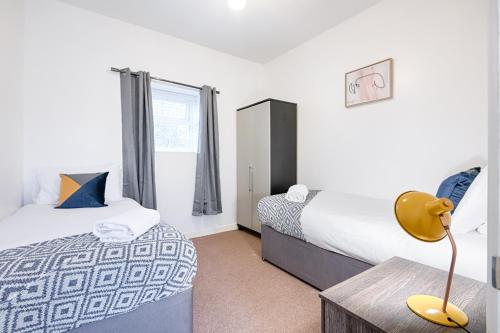a bedroom with two beds and a table with a lamp at Perfect Location with Parking -Jersey Lodge in Swansea