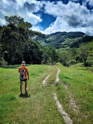 a man walking down a dirt road in a field at La Perla Negra - Black Pearl Eco Hostel in San Rafael