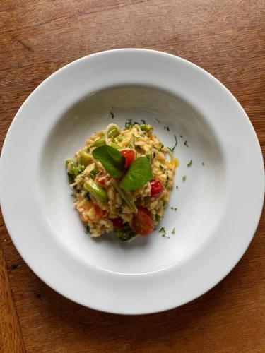a white bowl of food on a wooden table at Villa Bebek Hotel in Camburi
