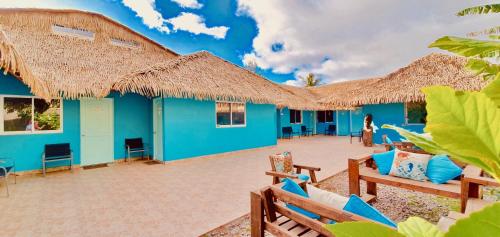 un bâtiment bleu avec des chaises et des toits de paille dans l'établissement Hotel & Apartments "CHEZ HIVA", à Hanga Roa