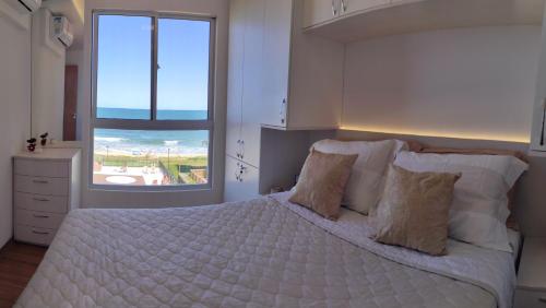 a bedroom with a large white bed with a window at Paraíso Frente ao Mar in Barra Velha