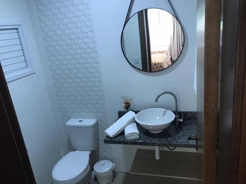 bagno con servizi igienici, lavandino e specchio di Flat Charme Gramado a Gramado