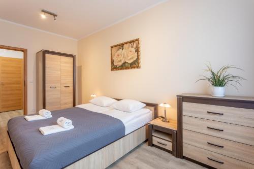 een slaapkamer met een bed en een dressoir met handdoeken bij Ambria Apartments Platan Complex II in Świnoujście