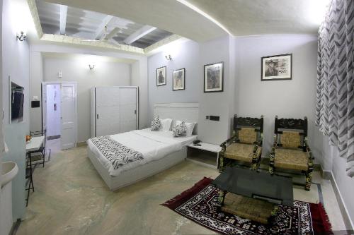 - une chambre blanche avec un lit et deux chaises dans l'établissement HOTEL 86B, à Kolkata