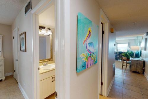 uma casa de banho com um lavatório e uma pintura na parede em 101 - Sandy Shores em St. Pete Beach