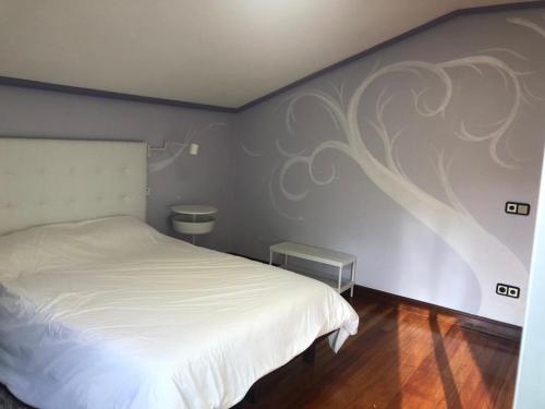 a bedroom with a white bed and a wall with a tree mural at Estancia Edurne in Mungia