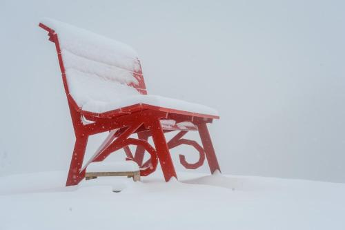a red chair covered in snow with a table at Chalet Everest - Luxury Apartments in Prato Nevoso