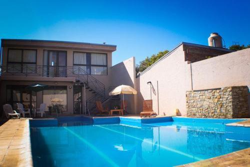 a swimming pool with a blue umbrella in front of a house at Cabañas Villa de Luján in San Rafael
