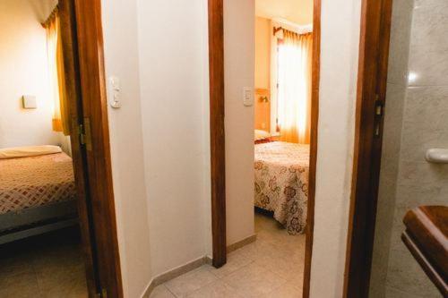 a hallway to a bedroom with two beds and a mirror at Cabañas Villa de Luján in San Rafael
