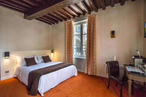 Un dormitorio con una cama y un escritorio y una ventana. en Logis du Parvis ***Face Cathédrale/in front of the Cathedral***, en Laon